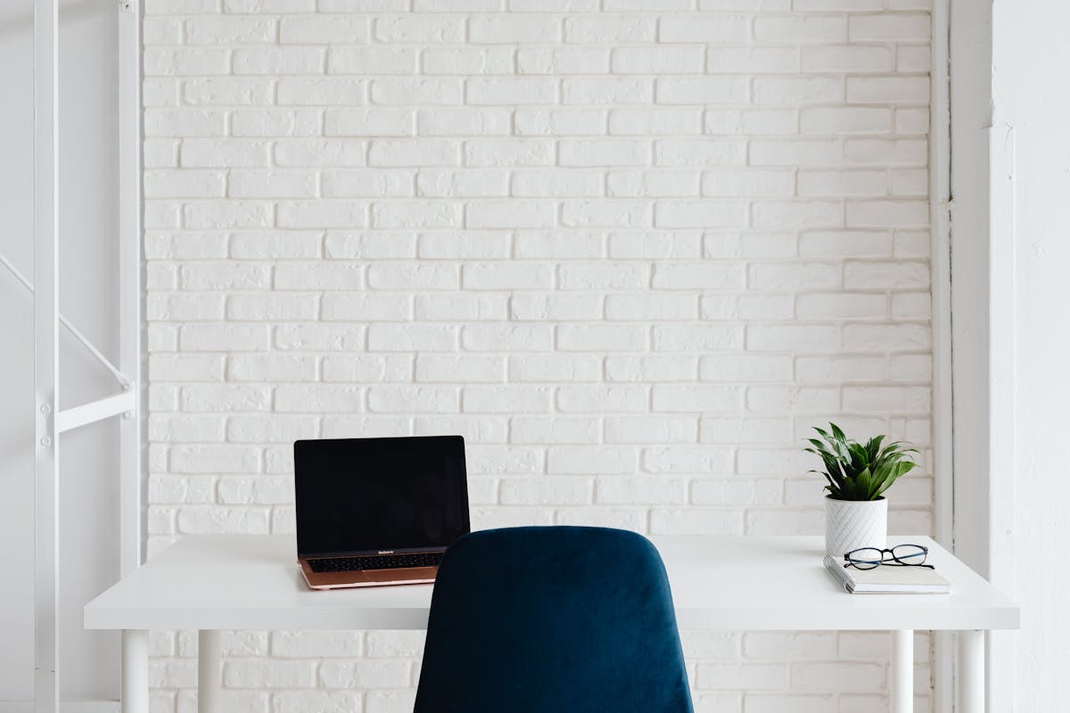 Heller Schreibtisch mit Laptop vor heller Wand